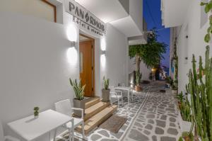 纳克索乔拉Panormos Hotel and Studios的白色的建筑,配有桌椅和植物