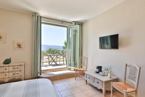 古尔Quintessence Provence的一间卧室设有一张床、一台电视和一个阳台。