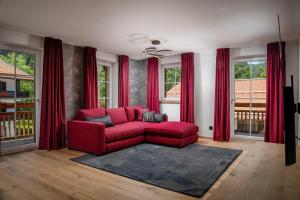 巴特维塞Luxury Apartments "R6 Tegernsee"的客厅的窗户前设有红色沙发