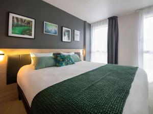 瓦讷Aparthotel & Spa Adagio Vannes的一间卧室设有一张大床和一个窗户。