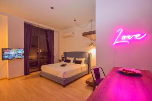 新山Cube 8teens by Nest Home的卧室配有一张床,墙上挂着 ⁇ 虹灯标志