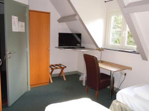 梅赫伦迈卡特酒店的一间卧室配有书桌、一张床和电视。