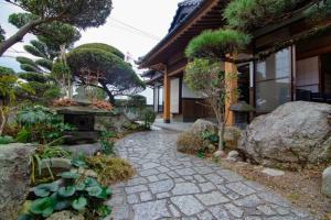 太宰府市太宰苑 - Dazaien Traditional Japanese houses的一座花园,房子前有一条石头走道