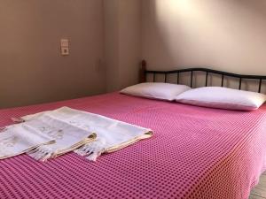 锡蒂亚Sergios Apartment的一张带粉红色棉被的床,配有两个枕头和报纸