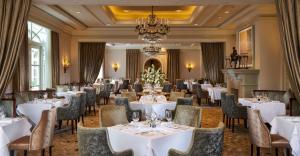 都柏林都柏林洲际酒店的一间配备有白色桌椅和吊灯的餐厅