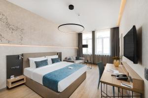 布达佩斯Hotel Vision Budapest by Continental Group的一间卧室配有一张床、一张书桌和一台电视。