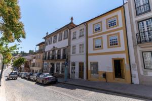 布拉干萨Secret Garden Suites in Bragança的街道上,有汽车停在建筑前