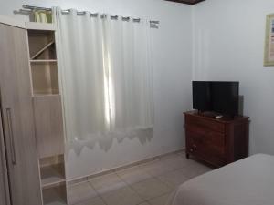 伊瓜苏Casa Aconchego Fóz的卧室配有白色的淋浴帘和电视
