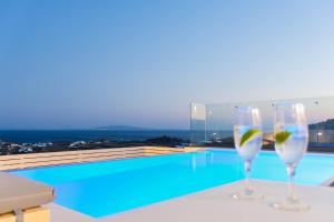 普拉迪斯亚罗斯Lofos Apartments的两个酒杯坐在游泳池旁的桌子上
