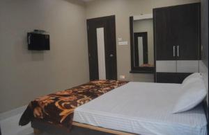 迪乌Premium hotel near Nagoa Beach的卧室配有一张床,墙上配有电视。