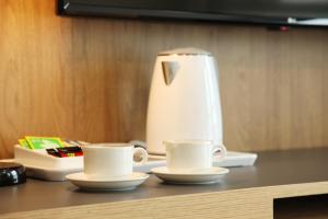 大田Hotel Skypark DaejeonⅠ的桌上的两杯咖啡,放一个榨汁机
