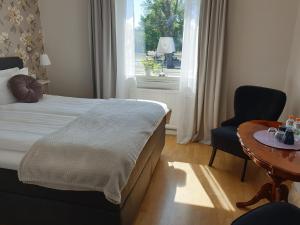 SmålandsstenarSmålandsstenar hotell的一间卧室配有一张床、一张桌子和一个窗户。