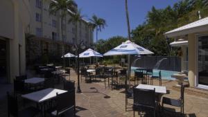 德班The Riverside Hotel的一组桌椅,在游泳池旁边配有遮阳伞