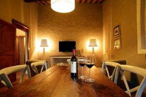 蒙塔尔奇诺Colle al Matrichese - Historic Winery的木桌旁的一瓶葡萄酒和两杯酒