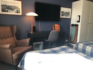 图尔库West Side Hotel的酒店客房配有一张床、一把椅子和一台电视。