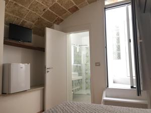 乌真托Ugento Dimora的一间卧室配有一张床、一台电视和一个窗口