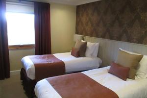 巴洛赫Cameron House Lodge on Loch Lomond的酒店客房设有两张床和窗户。