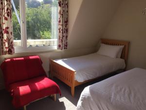 普里茅斯Barbican Reach Guest House的一间卧室设有两张床、一把椅子和一个窗户。
