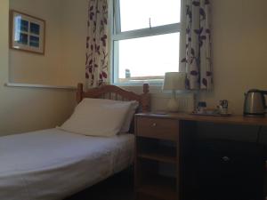 普里茅斯Barbican Reach Guest House的一间卧室配有一张床、一个窗口和一张书桌