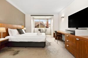 墨尔本墨尔本大都会酒店的一间卧室配有一张床和一张书桌及电视