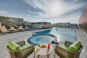 迪拜URBAN Al Khoory Hotel的屋顶游泳池,配有椅子和桌子