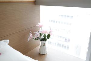 香港香港奥斯酒店的窗边桌子上一个花瓶,上面有粉红色的花朵