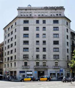 巴塞罗那格兰大道费萨租赁公寓的一座白色的大建筑,前面有汽车停放