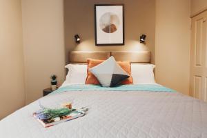 塔姆沃思Victoria Apartments Tamworth的卧室配有带橙色枕头的白色床