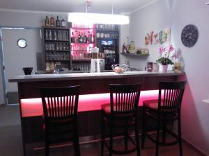 上隆维茨丘利纳酒店的酒吧设有四把椅子和一个带粉红色照明的吧台