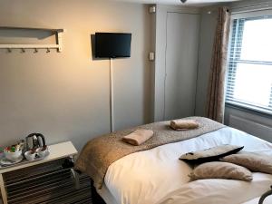 布莱顿霍夫EI8HT Brighton Guest Accommodation的卧室配有一张壁挂式平面电视的床。