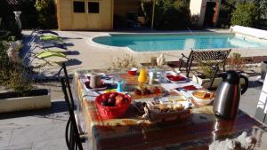 布尔圣昂代奥l'oustau bonur的游泳池旁的餐桌上放着食物