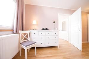 于尔齐希Gästehaus C.H.Berres Ürzig-Mosel的卧室配有白色梳妆台和椅子