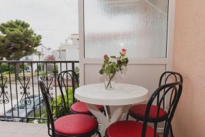 沃迪切Apartments Josip Vodice的一张桌子和椅子,阳台上有一个玫瑰花瓶