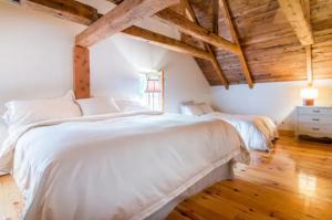 斯托纳姆Cottage Jacques Cartier的卧室设有一张白色大床和木制天花板。