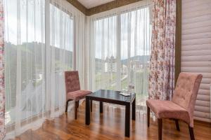 布克维Hotel Pid Strihoju的窗户间配有一张桌子和两把椅子