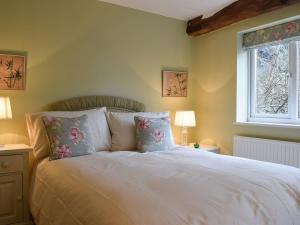 埃文河畔斯特拉特福Lovely old cottage的卧室配有带枕头的白色床和窗户。