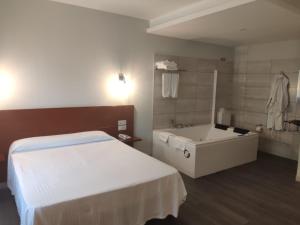 卡尔达斯·德·雷斯Motel Caldas的一间卧室配有一张床、一个浴缸和一个水槽