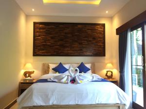 乌布Cahaya Guest House的一间卧室配有白色床和蓝色枕头