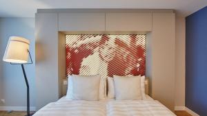巴塞尔韦特施泰因酒店的卧室配有一张挂有红色壁画的床