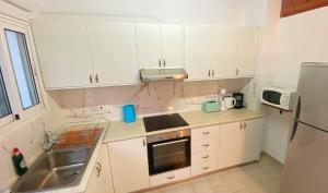 拉基JustSmile - Seaview Maisonette in Latchi的厨房配有白色橱柜、水槽和冰箱。