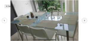 卡萨布兰卡Villa moderne avec piscine, front de mer的玻璃餐桌,上面摆放着白色的椅子和鲜花