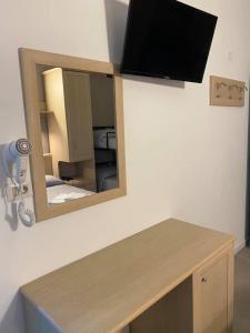 丽都迪萨维奥Hotel Rex的墙上的镜子,配有桌子和电视