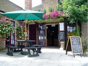 CuckfieldThe Wheatsheaf Inn的大楼前的野餐桌和雨伞