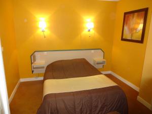 卡布尔Hôtel La Champagne Ardenne Cabourg的卧室配有一张带两盏灯的墙壁床。