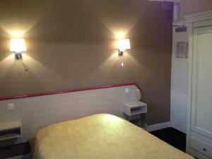 卡布尔Hôtel La Champagne Ardenne Cabourg的一间房间,墙上有一张床和两个灯