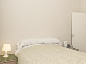 亨顿Chumleigh Lodge Hotel Ltd.的一间卧室配有一张带白色床单和一盏灯的床。