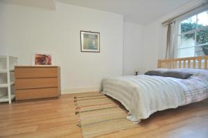伦敦Large Garden flat in the heart of Islington的一间卧室配有一张床、一个梳妆台和一扇窗户。