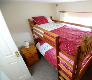 布什米尔斯Village Cottage Bushmills的一间卧室配有双层床,铺有红白色床单
