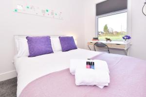 克鲁Townhouse @ Henry Street Crewe的卧室配有白色床、紫色枕头和窗户