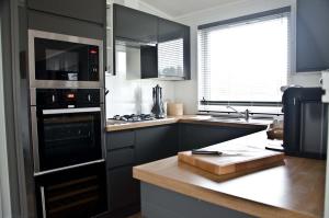 约克Hollicarrs - Honeycomb Lodge的厨房配有黑色橱柜和炉灶烤箱。